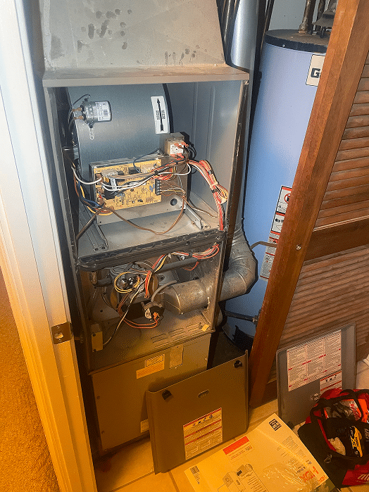 An open furnace unit during a repair service in a Hilliard, Ohio home, revealing the internal control board, blower motor, and wiring with a technician's tool bag nearby.