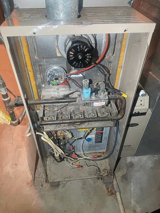 Internal view of a furnace during a diagnostic service in Hilliard, Ohio, showing the control board, capacitor, and blower assembly with a technician's tool bag on site.