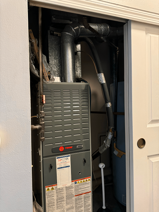 A Trane gas furnace installed in a utility closet of a Hilliard, Ohio home, featuring a service record tag and showing the venting and gas line connections.